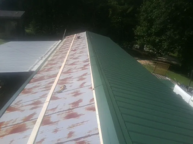 Old rusted panels beside newly installed green metal roofing — Wind Damage Roof Repair by Roofing Brothers in Moody