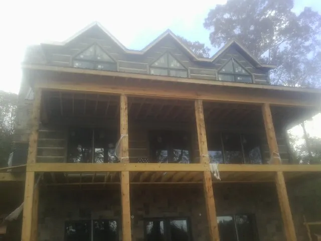 Dormers and porch framing on a large log home under construction — Roof Coating work by our crew in Moody