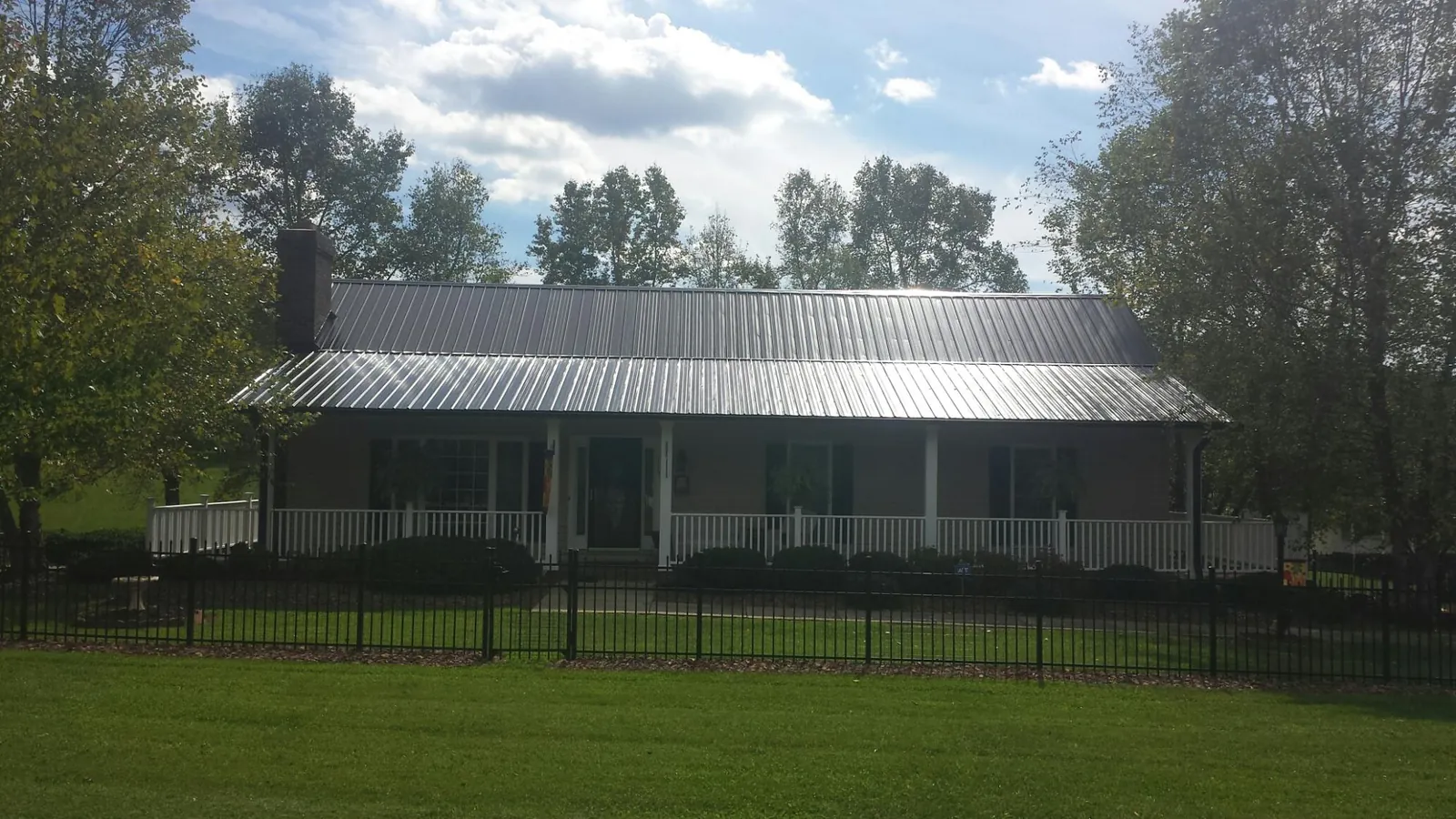 Gray metal roof on a brick ranch with a full width front porch — Gutter Guard Installation work by our crew in Moody