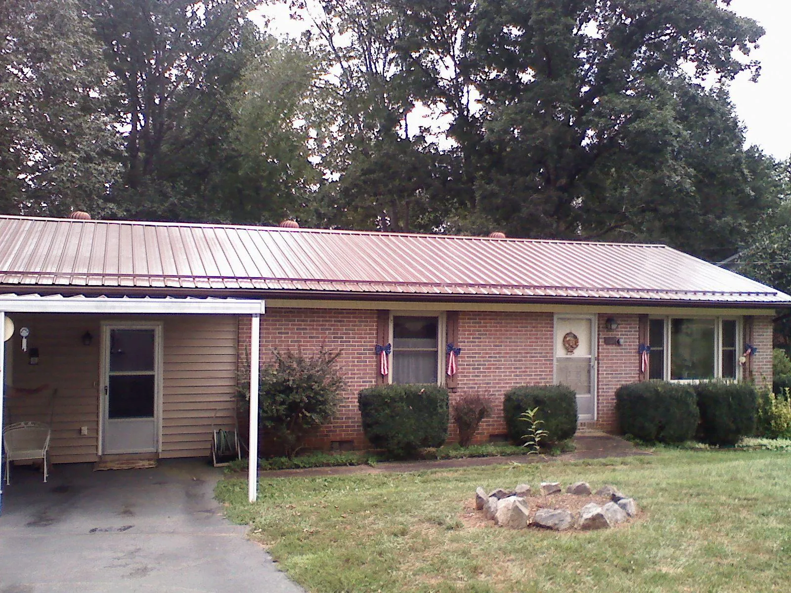 Bronze metal roof and carport on a brick ranch home — Roof Repair work by our crew in Moody