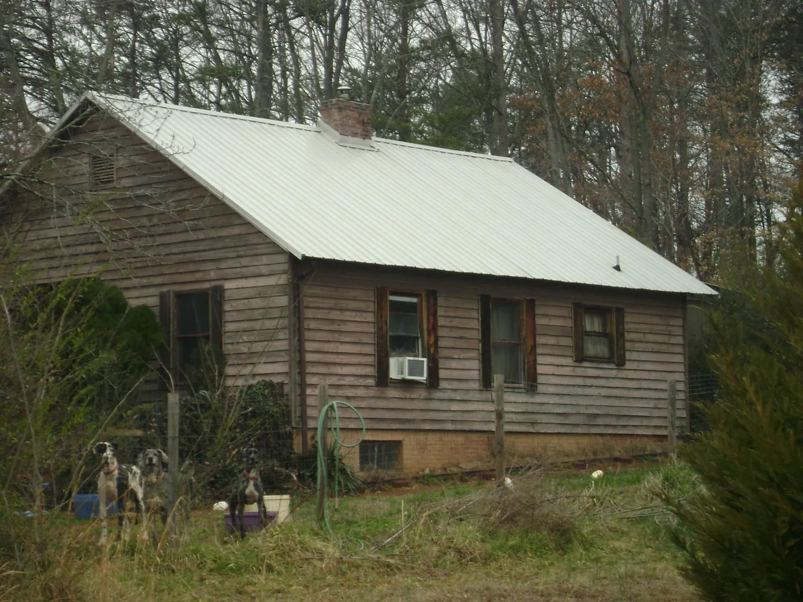 White metal roof on an old wood sided farmhouse, from a Metal Roof Installation job in Moody